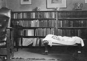 Baby Audrey in cradle in booklined room in the Old Nailshop