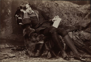 Wilde in velvet and furs reclining on a sofa in elaborate studio interior. Photograph by Sarony, circa 1882.