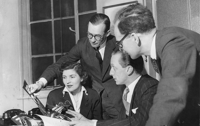 Eagle Editorial Meeting: Ellen Vincent, assistant editor; Macdonald Hastings, Eagle 'Special Investigator'; Marcus Morris, the editor; and Michael Gibson, art editor. A version of this photo appeared in the April 9, 1954 issue. Eagle Editorial Meeting. Left to right: Ellen Vincent, assistant editor; Macdonald Hastings, Eagle 'Special Investigator'; Marcus Morris, the editor; and Michael Gibson, art editor. A version of this photo appeared in the April 9, 1954 issue.