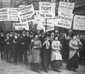 Photograph of striking garment workers carrying placards, with women at the front.